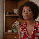 Anne-Marie McCoy (Vanessa Estelle Williams) wears a red, green, and orange flowered dress in a scene from 2021's Candyman.